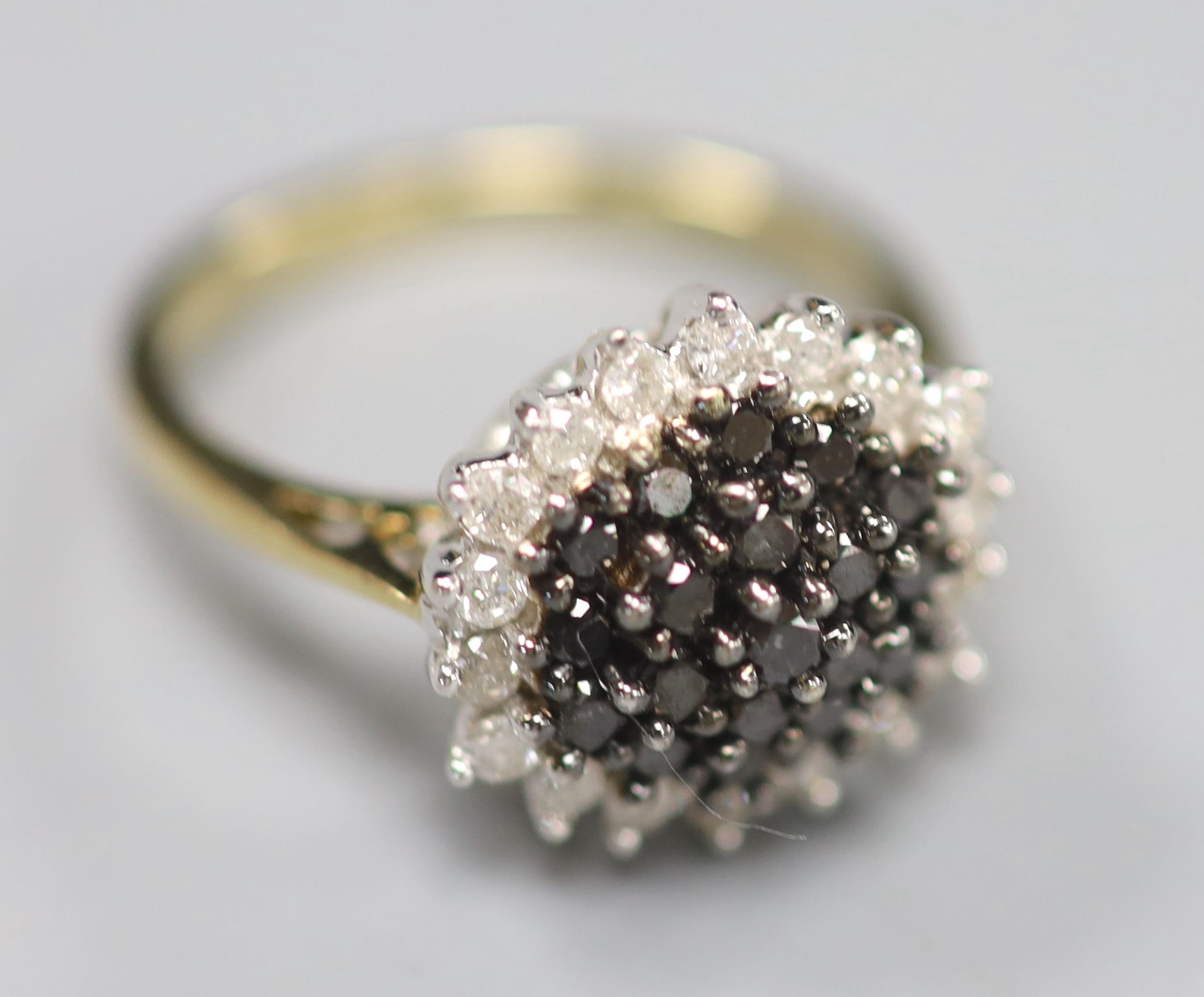 A modern 18ct gold, black and white diamond cluster set dress ring, size P, gross 4.2 grams.